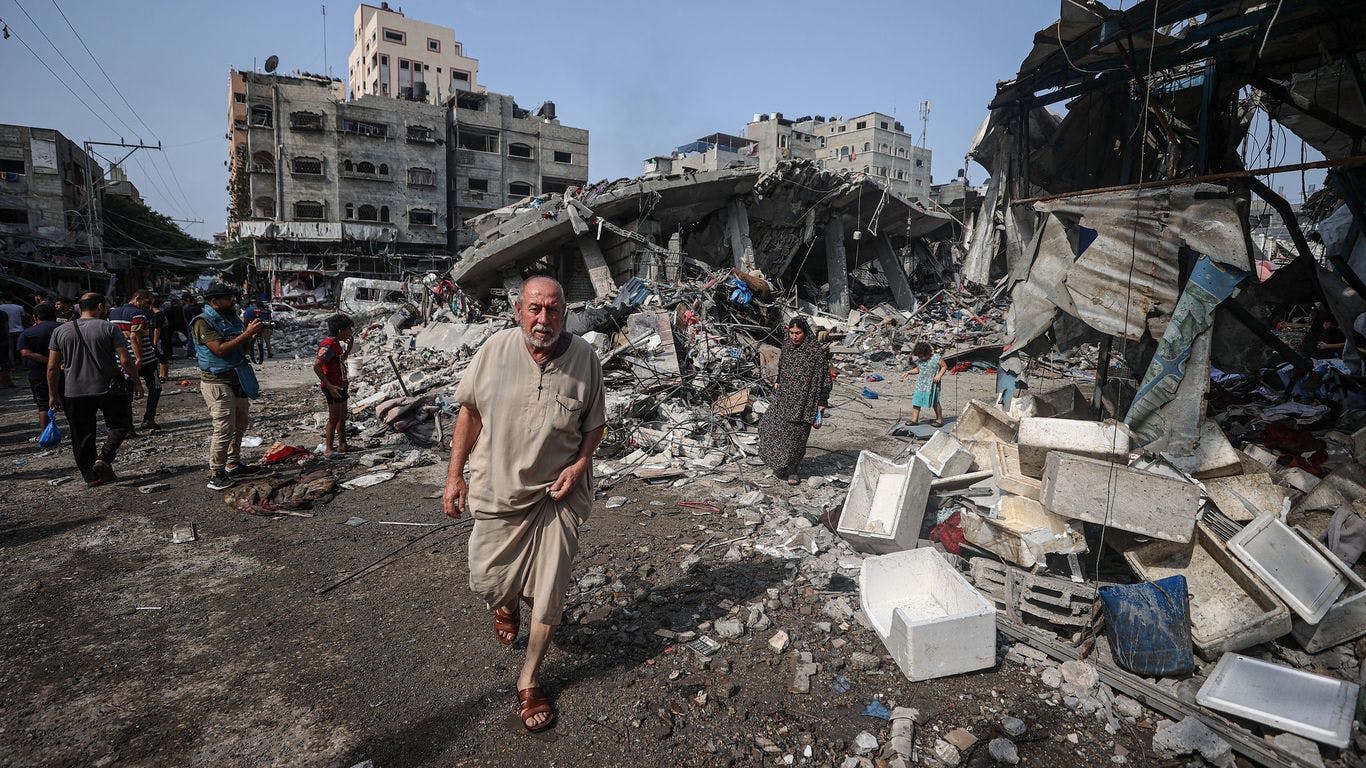 Palestinians walk through the rubble of a refugee camp