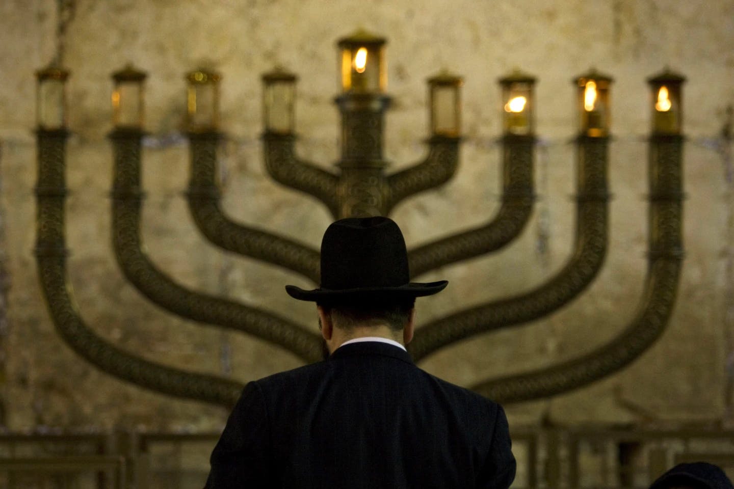 A Jewish mans stands in front of a menorah