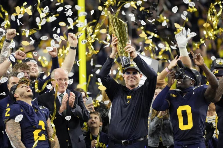 Jim Harbaugh holds the CFP national championship trophy