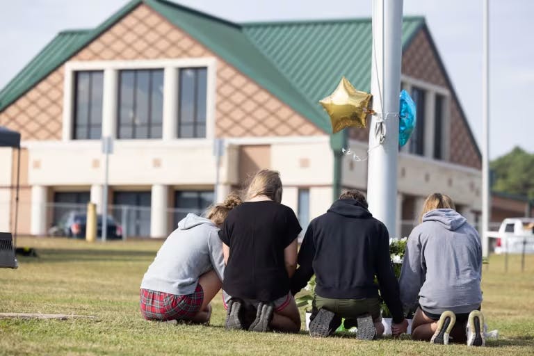 Students kneel in front of a memorial in Georgia